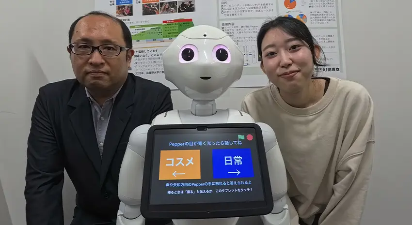 Pepper作品と学内学習発表会で掲示したポスターと共に、STREAMチャレンジにファイナリストに選ばれた際に撮影。星川さん（右）と指導担当の渡邊 紀文先生（左）